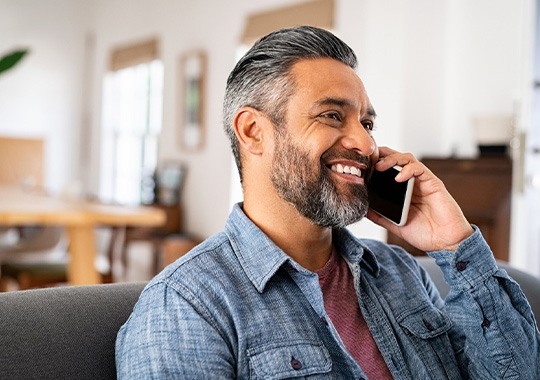 Man smiling while talking on phone at home