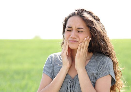 Woman standing outside, experiencing jaw pain
