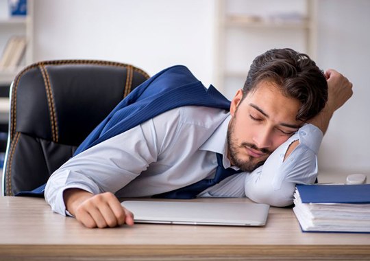 Exhausted man sitting at his work desk
