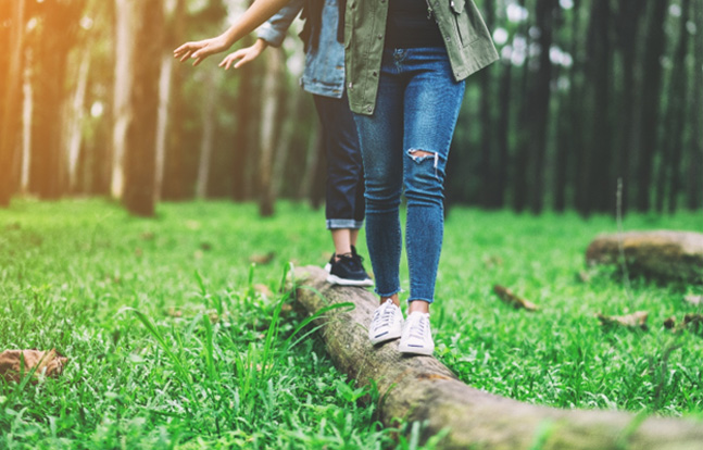 Two people balancing while walking on log