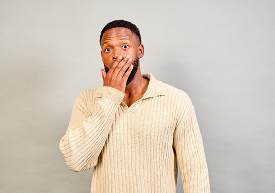 Man covering his mouth, wearing concerned expression