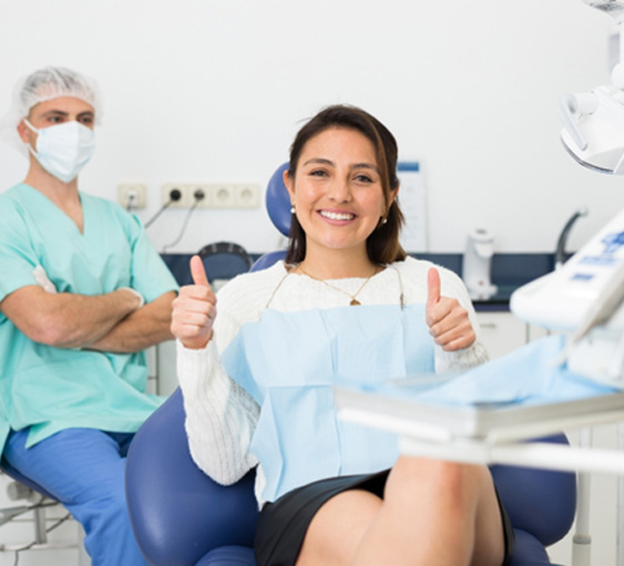 Happy dental patient making double thumbs up gesture