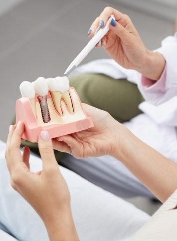 Dentist showing a dental implant model to a patient