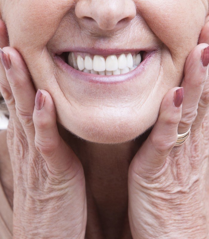 Close up of smiling senior woman touching her face