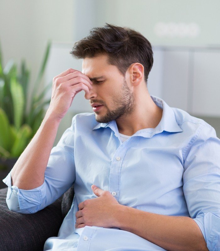 Man pinching the bridge of his nose and holding his stomach