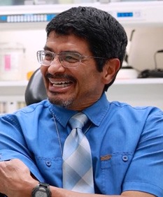 Man in light blue collared shirt and tie grinning in Owasso dental office