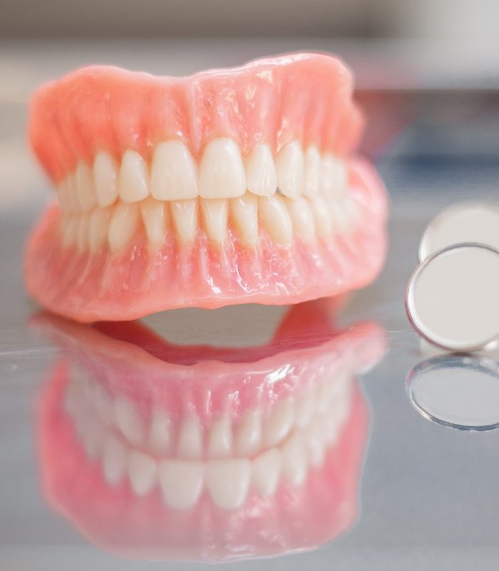 Full dentures resting on table with two dental mirrors