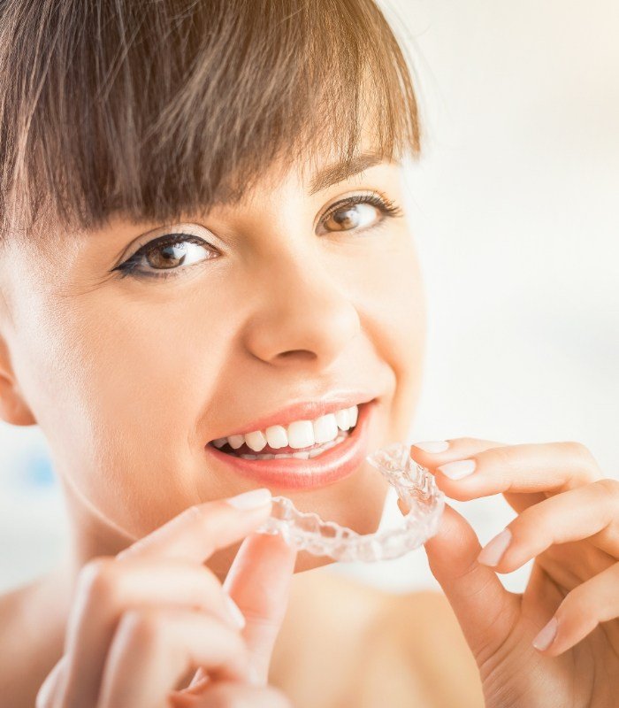 Woman placing a clear aligner over her teeth