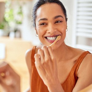 Woman smiling while brushing her teeth