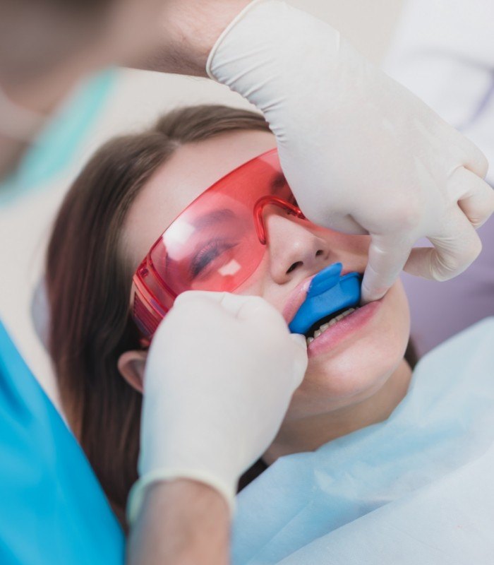 Young woman in dental chair with fluoride trays on her teeth