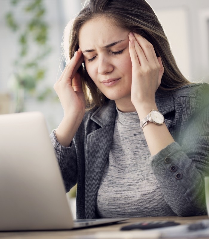 Woman sitting at desk touching her temples in frustration