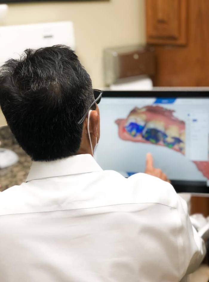 Doctor Lim looking at digital models of teeth on computer screen