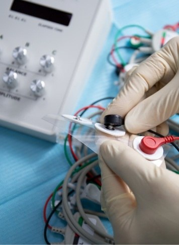 Gloved hands working with a system of wires and electrodes