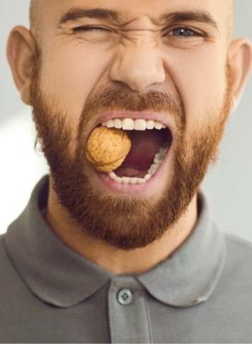 Man holding a walnut between his teeth
