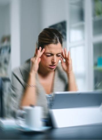 Woman sitting at desk touching her temples