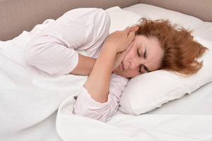 Red-haired woman in bed with jaw pain