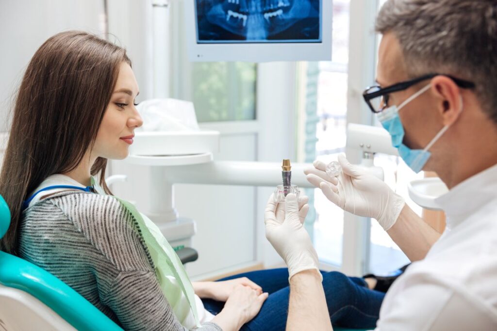 A dentist showing a female patient a model of a dental implant